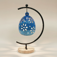 Load image into Gallery viewer, (agate blue)
Back of the agate blue floral luminary by Ahava Memorials, handcrafted with ashes and illuminated by a candle through its delicate ceramic details.