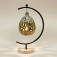 Load image into Gallery viewer, (jasper gold)
Back of the jasper gold floral luminary by Ahava Memorials, handcrafted with ashes and illuminated by candlelight on its ceramic stand as a radiant remembrance piece.