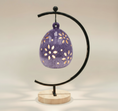 Load image into Gallery viewer, (lavender)
Back view of the lavender floral luminary by Ahava Memorials, handcrafted with ashes and shown illuminated from within by a candle as an elegant memorial artwork.