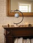 Load image into Gallery viewer, Ahava Memorials handcrafted ceramic ball ornament made with ashes, displayed in a softly lit home setting beside candles as a peaceful cremation keepsake.
