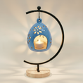 Load image into Gallery viewer, (agate blue)
Agate blue ceramic floral luminary made with ashes, handcrafted by Ahava Memorials with a glowing candle inside and elegant floral cutouts on its stand.
