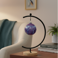 Load image into Gallery viewer, Ahava Memorials handcrafted ceramic paw ball ornament made with pet ashes, displayed beside a photo and candle as a heartfelt cremation keepsake.

