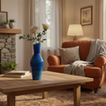 Load image into Gallery viewer, Living room with a blue vase on a wooden coffee table, orange armchair, and stone fireplace.
