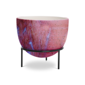 (sunstone red)
A round modern planter with a pink and purple marbled pattern, sitting on a black metal stand with a cylindrical shape.