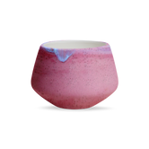 (sunstone red)
A pink ceramic tulip planter with a glazed finish and a handle on the side.